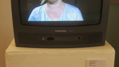 Fernseher auf einem Podest, darin eine Frau zu sehen