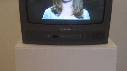 Fernseher auf einem Podest, darin eine Frau zu sehen