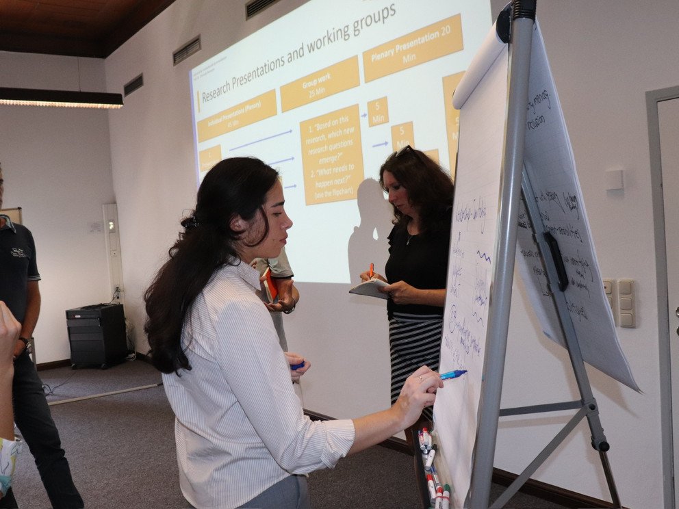 Participants in a working group, female writing on a flipchart