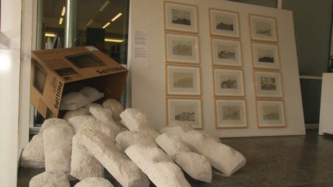 Wand voller Bildern neben einem umgest&uuml;rzten Karton aus dem wei&szlig;e Bl&ouml;cke fallen