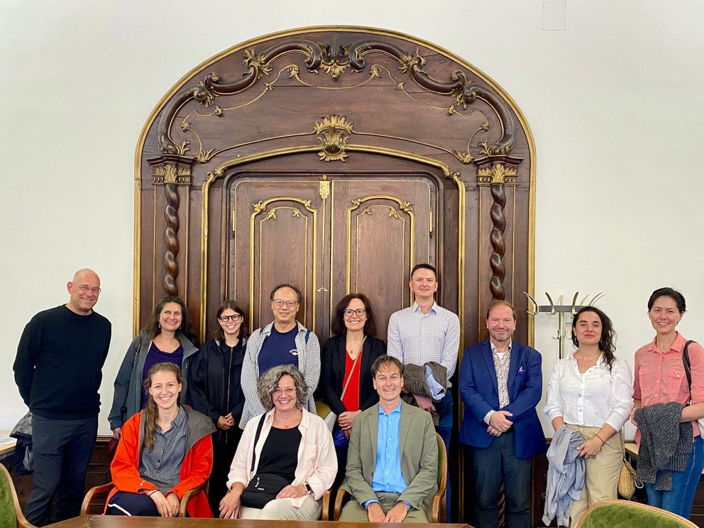 Participants in front of a wooden door inside the historical rooms of the symposium
