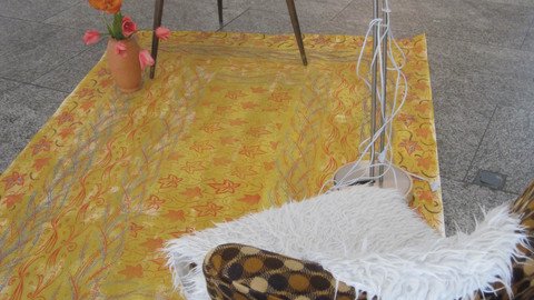 Fotografie: Teppich, Sessel und ein Fernseher auf einem Tisch