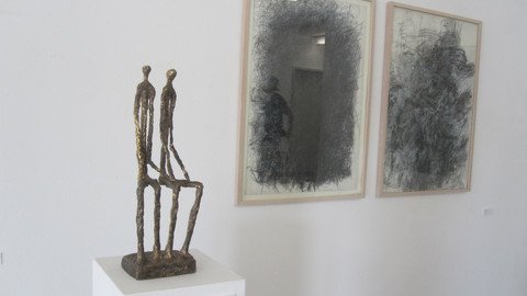 Skulptur auf einer S&auml;ule neben gerahmten Bildern an der Wand