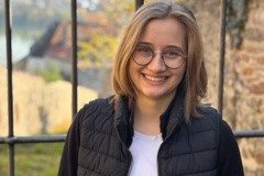 Studentin vor einem Metallzaun